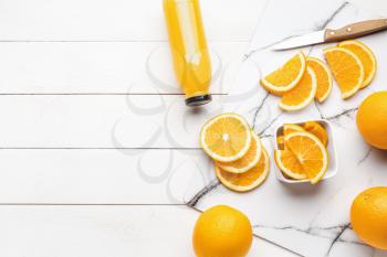 Fresh oranges with bottle of juice on white table�
