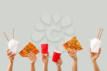 Many hands with delivery food on grey background�