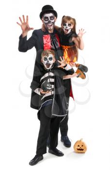 Father with children in Halloween costumes and with pumpkins on white background�
