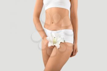 Young woman with flower on grey background. Gynecology concept�