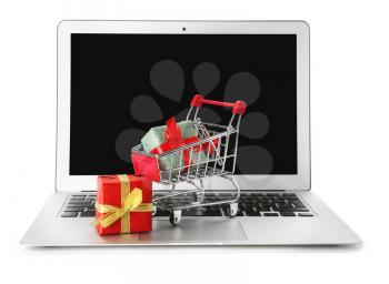 Laptop and small cart with gift boxes on white background. Internet shopping concept�
