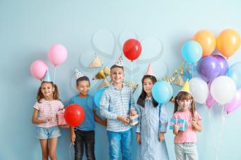 Little children with Birthday gifts and air balloons on color background�