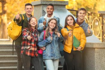 Group of teenage students showing thumb-up outdoors�