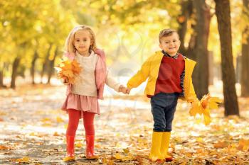 Cute little children with leaves in park on autumn day�