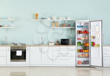 Open big fridge with products in interior of kitchen�