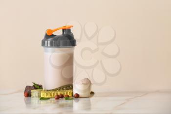 Bottle of protein shake with measuring tape on light table�