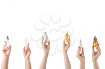 Female hands with different cosmetic products in bottles on white background�