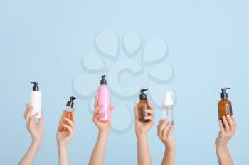 Female hands with different cosmetic products in bottles on color background�