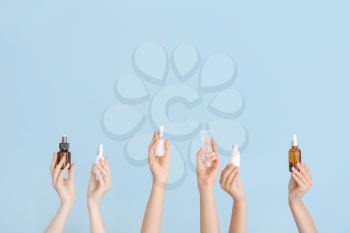 Female hands with different cosmetic products in bottles on color background�