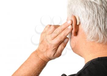 Mature man with hearing aid on white background�