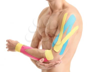 Sporty man with physio tape applied on arm against white background, closeup�
