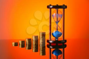 Hourglass with coins on color background�