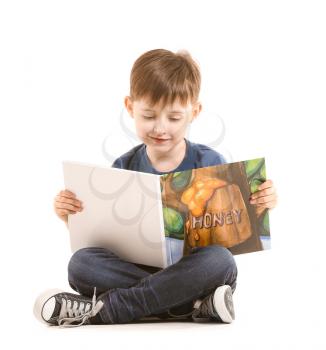 Cute little boy reading book on white background�