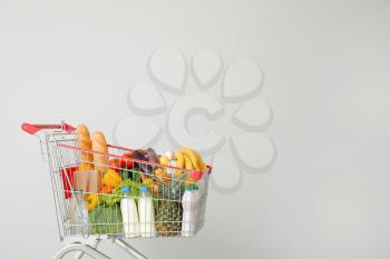 Shopping cart with products near light wall�
