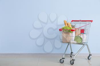 Shopping cart with products near color wall�