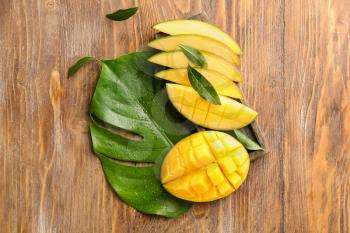 Cut mango fruit on wooden background�