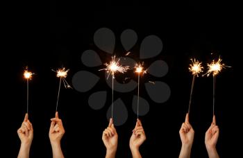 Female hands with Christmas sparklers on dark background�