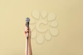 Female hand with microphone on color background�