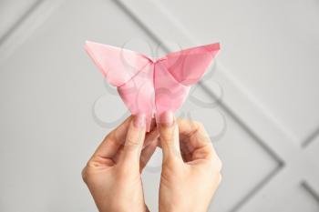 Female hands with origami butterfly on light background�