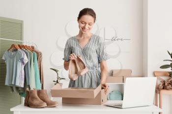 Young woman preparing parcel for client in office�