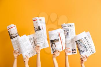 Female hands with newspapers on color background�