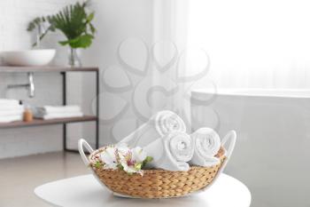 Basket with soft towels on table in bathroom�