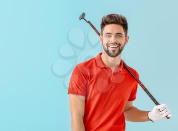 Handsome male golfer on color background�