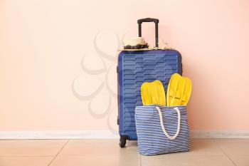 Suitcase and beach accessories near color wall. Travel concept�