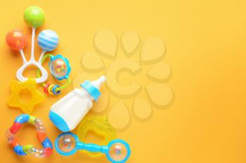 Bottle of milk for baby and toys on color background�