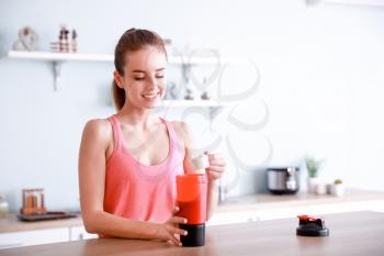 Sporty young woman making protein shake at home�