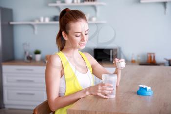 Sporty young woman making protein shake at home�