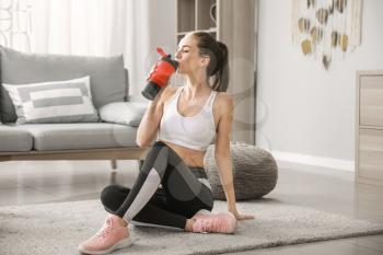 Sporty young woman with protein shake at home�