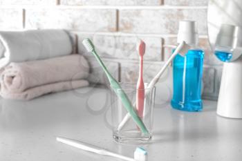 Holder with tooth brushes on table in bathroom�