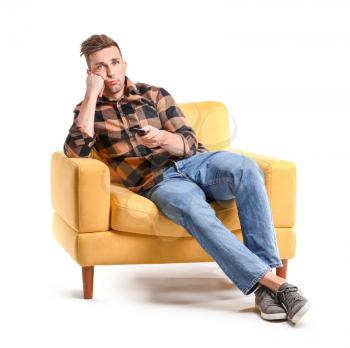 Bored man watching TV while sitting in armchair on white background�