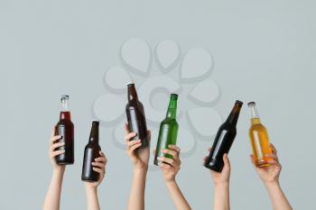 Hands with bottles of beer on grey background�