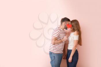 Happy young couple with red heart on color background. Valentine's Day celebration�
