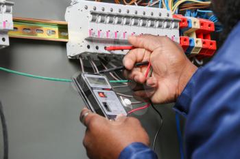 African-American electrician performing wiring in distribution board, closeup�