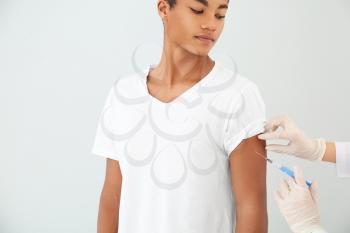 Doctor vaccinating teenage boy on white background�
