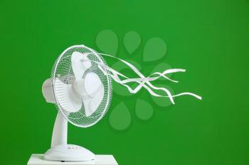 Electric fan with fluttering ribbons on color background�