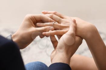 Young man putting ring on finger of his fiancee after marriage proposal, closeup�