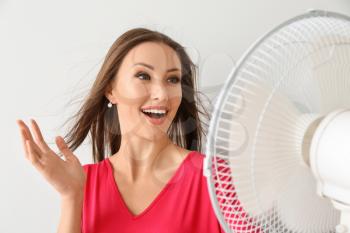 Happy woman with electric fan on white background�