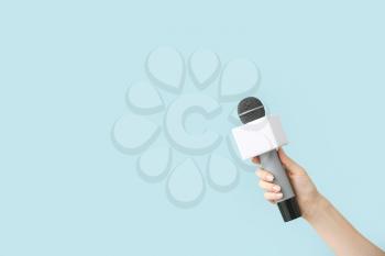 Journalist's hand with microphone on color background�