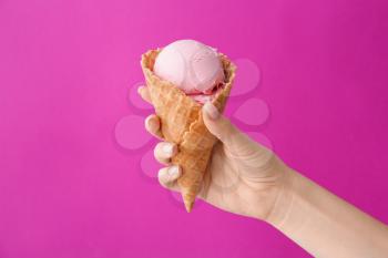 Female hand with sweet ice-cream on color background�