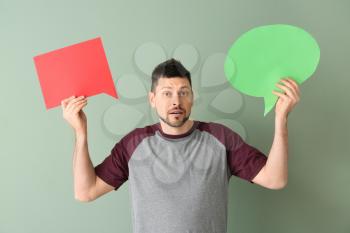 Man with blank speech bubbles on color background�