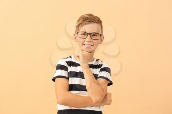 Cute little boy with eyeglasses on color background�
