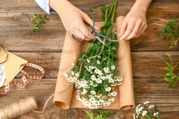 Female florist making beautiful bouquet on wooden background�
