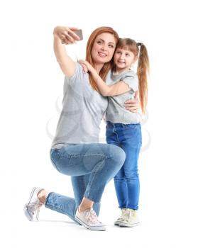Woman and her little daughter taking selfie on white background�