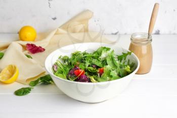 Bowl with vegetable salad and jar of tasty tahini on table�