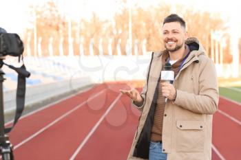 Male reporter with microphone at the stadium�