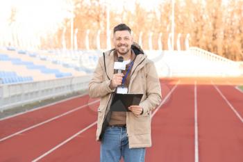 Male reporter with microphone at the stadium�